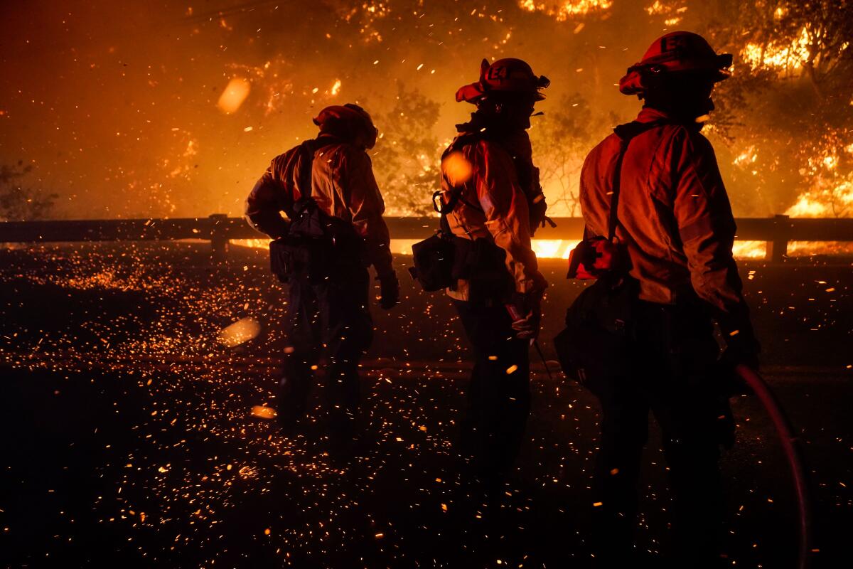 Firefighters turn to shield themselves from embers  as they battle the Bond fire.