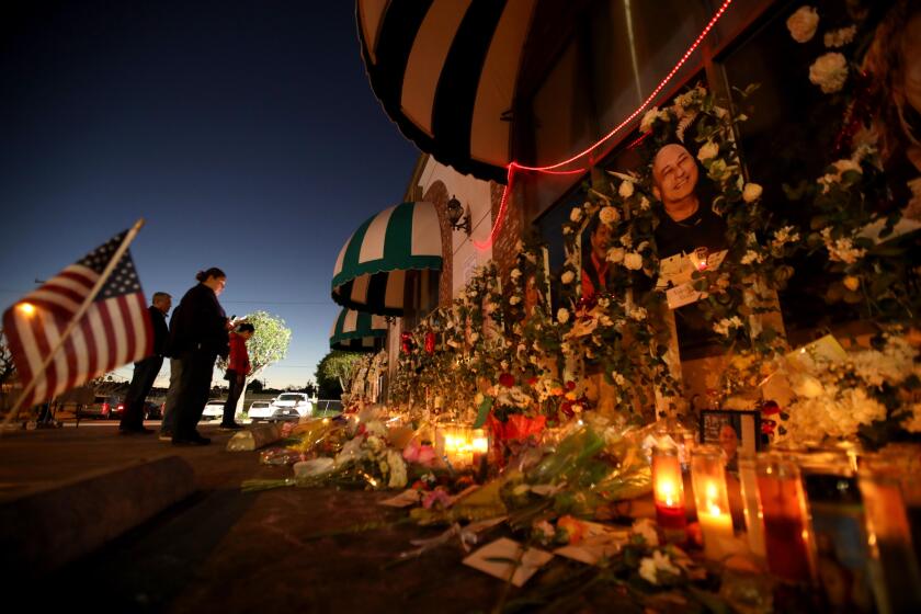 MONTEREY PARK, CA - JANUARY 26, 2023 - - People pay their respects at the memorial for 11 people who died in a mass shooting during Lunar New Year celebrations outside the Star Ballroom Dance Studio in Monterey Park on January 26, 2023. (Genaro Molina / Los Angeles Times)