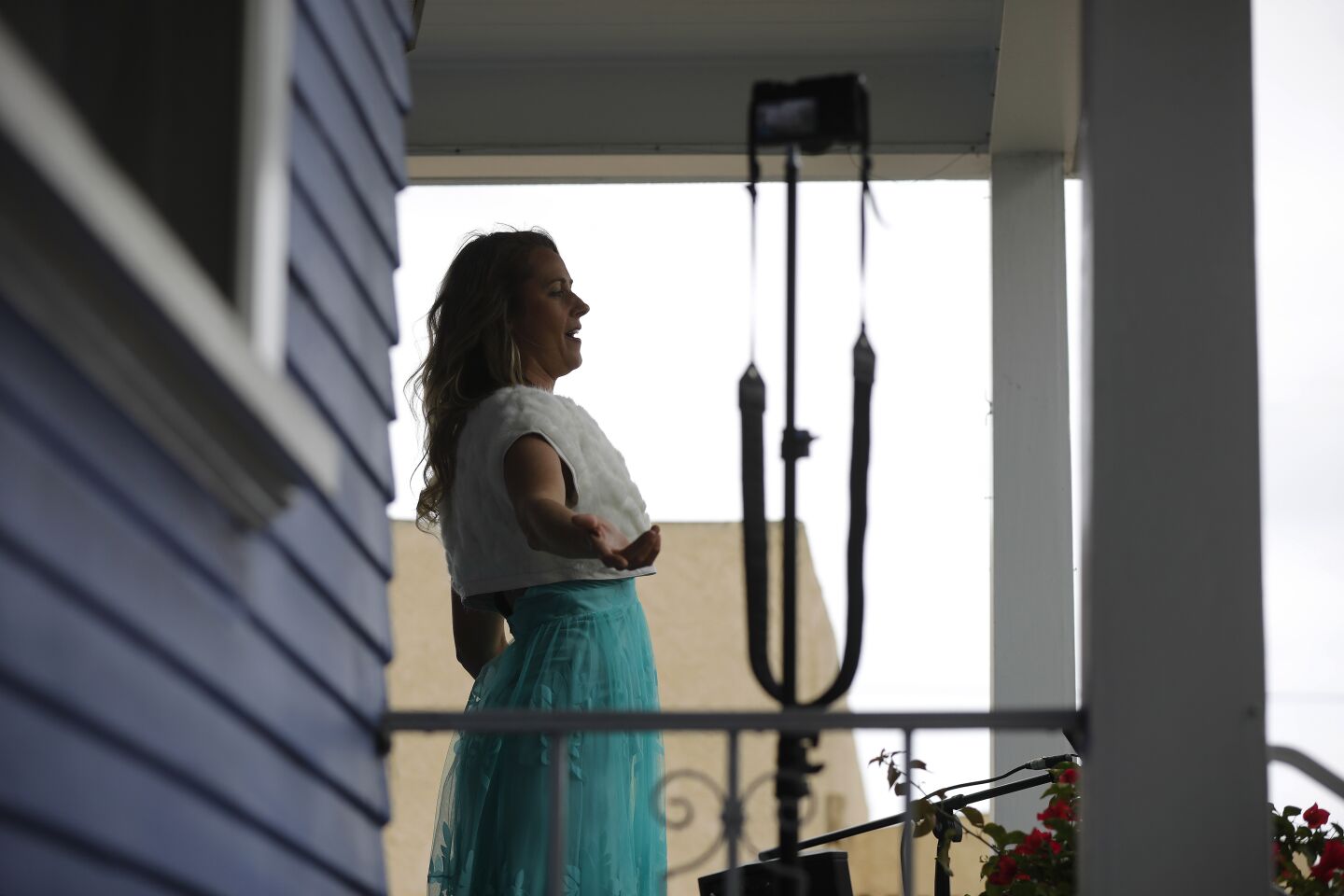 Opera singer Victoria Robertson, a soprano, sings from the porch of her North Park home on April 19, 2020. For the second week in a row, Robertson performed for 15 minutes to a crowd, keeping their distance from each other on the street below.