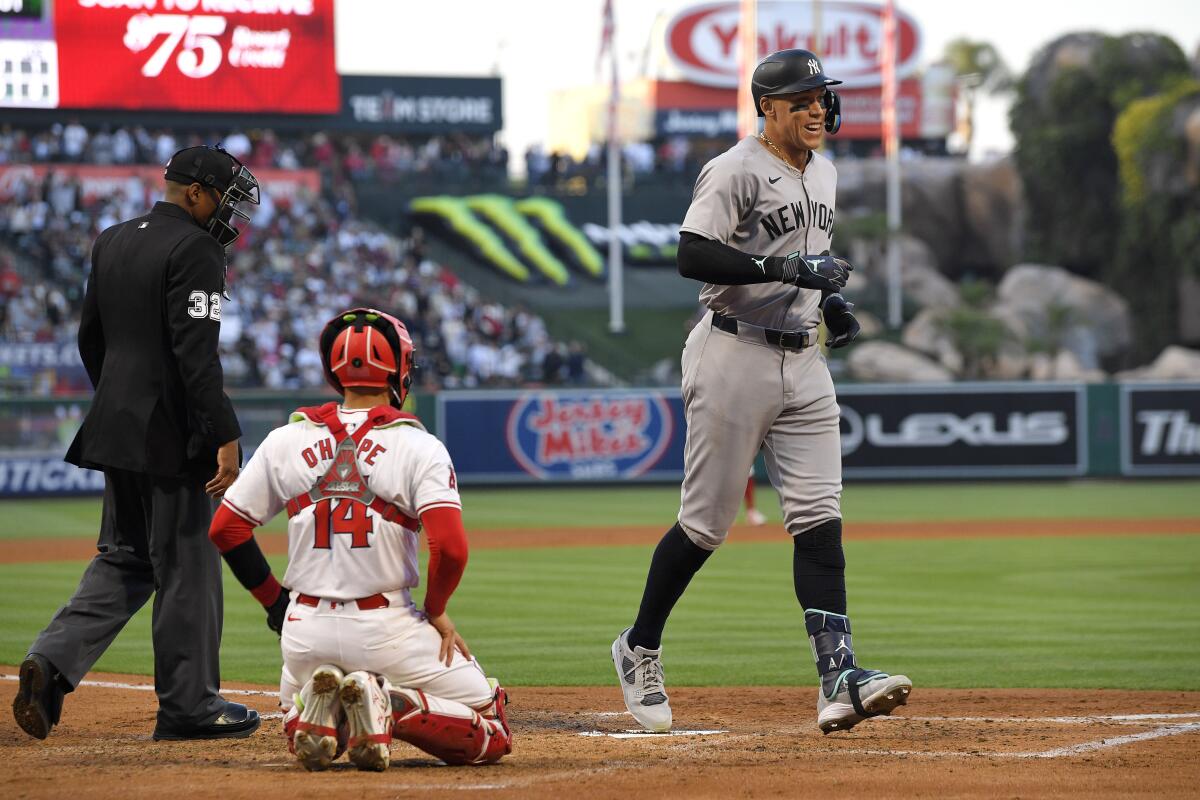 New York Yankees star Aaron Judge crosses the plate near the umpire and Angels catcher Logan O'Hoppe, crouching