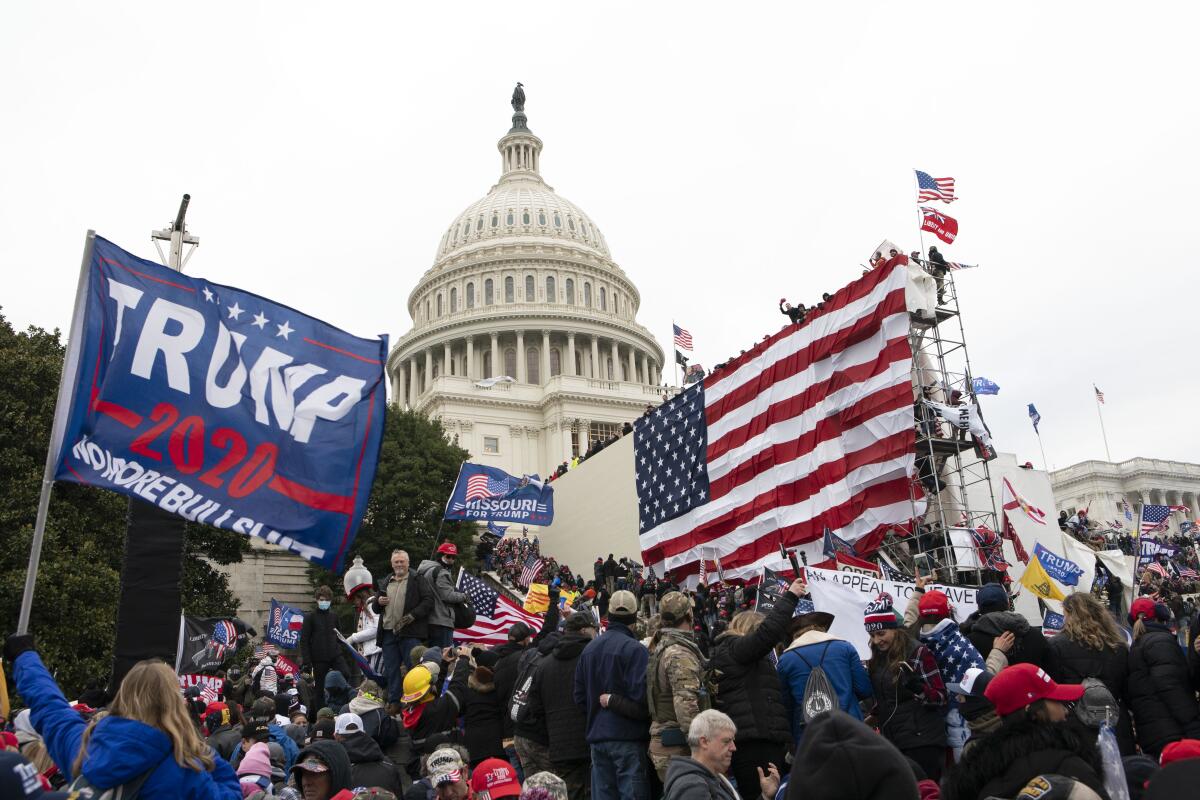 Insurrectionists stand outside the U.S. Capitol.