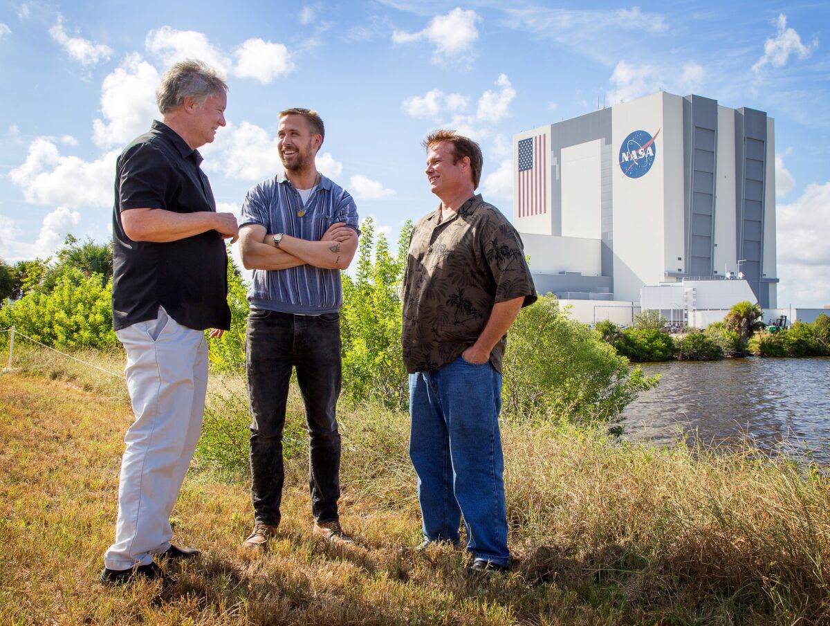 Ryan Gosling, center, with astronaut Neil Armstrong's sons Rick Armstrong, left, and Mark Armstrong at the Kennedy Space Center with the vehicle assembly building in the background, where the Saturn V rocket was stacked and then moved out to the launch pad.