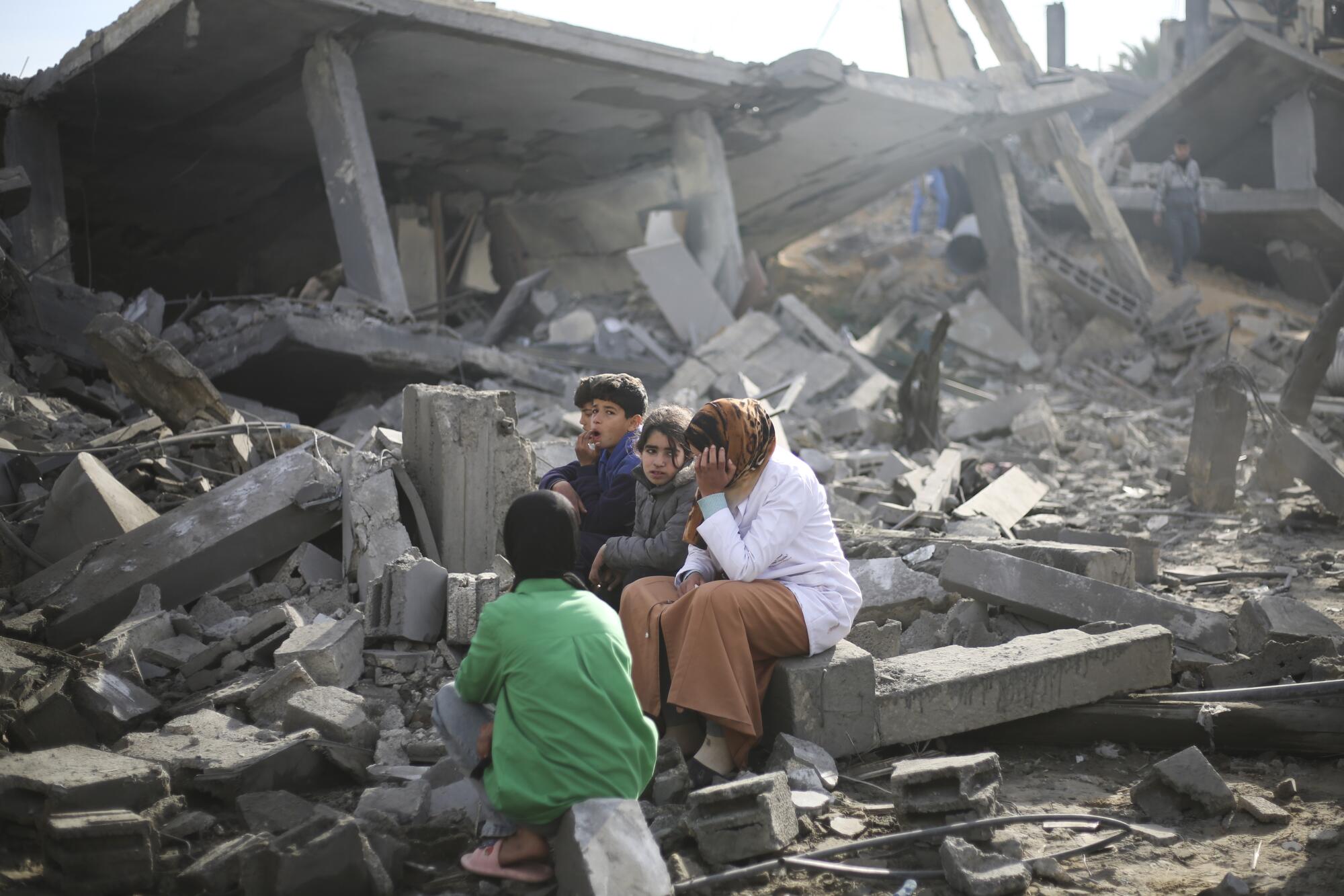 Palestinians sit next to the rubble after the Israeli bombardment