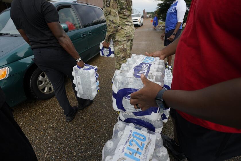 ARCHIVO – Voluntarios entregan botellas de agua a la gente en un centro de distribución en Jackson, Mississippi, el 7 de septiembre de 2022. (AP Foto/Rogelio V. Solis, Archivo)