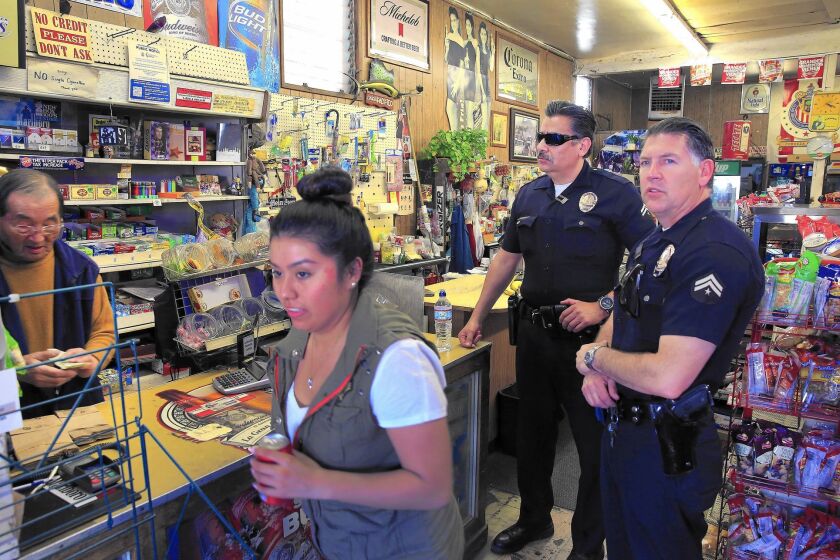 Hollenbeck Division Officers Dan Rios, right, and Joe Chacon visit with market owner Soo Rah, far left, while on patrol in Los Angeles.
