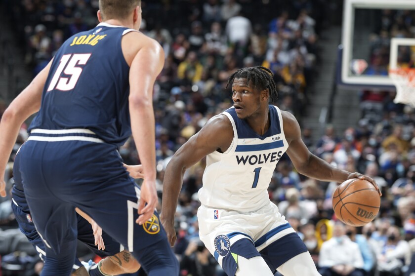 Minnesota Timberwolves forward Anthony Edwards, right, drives the lane as Denver Nuggets center Nikola Jokic looks on in the first half of an NBA basketball game Wednesday, Dec. 15, 2021, in Denver. (AP Photo/David Zalubowski)