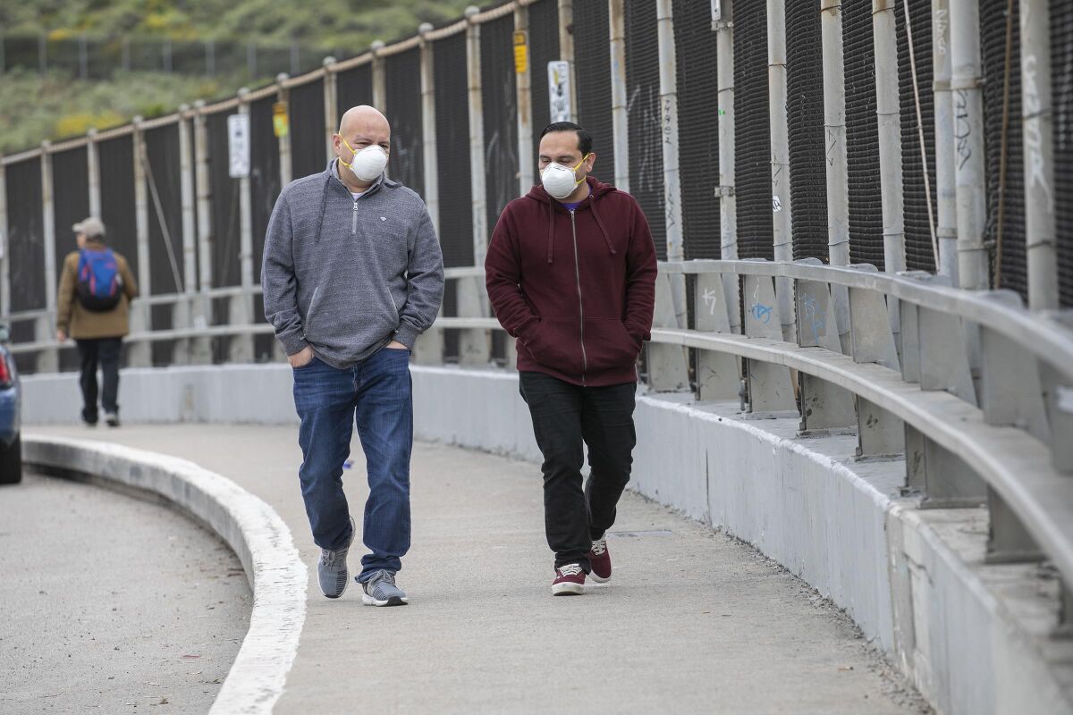 Two men walk along Camino de la Plaza in San Ysidro, the San Diego border neighborhood, on Friday.