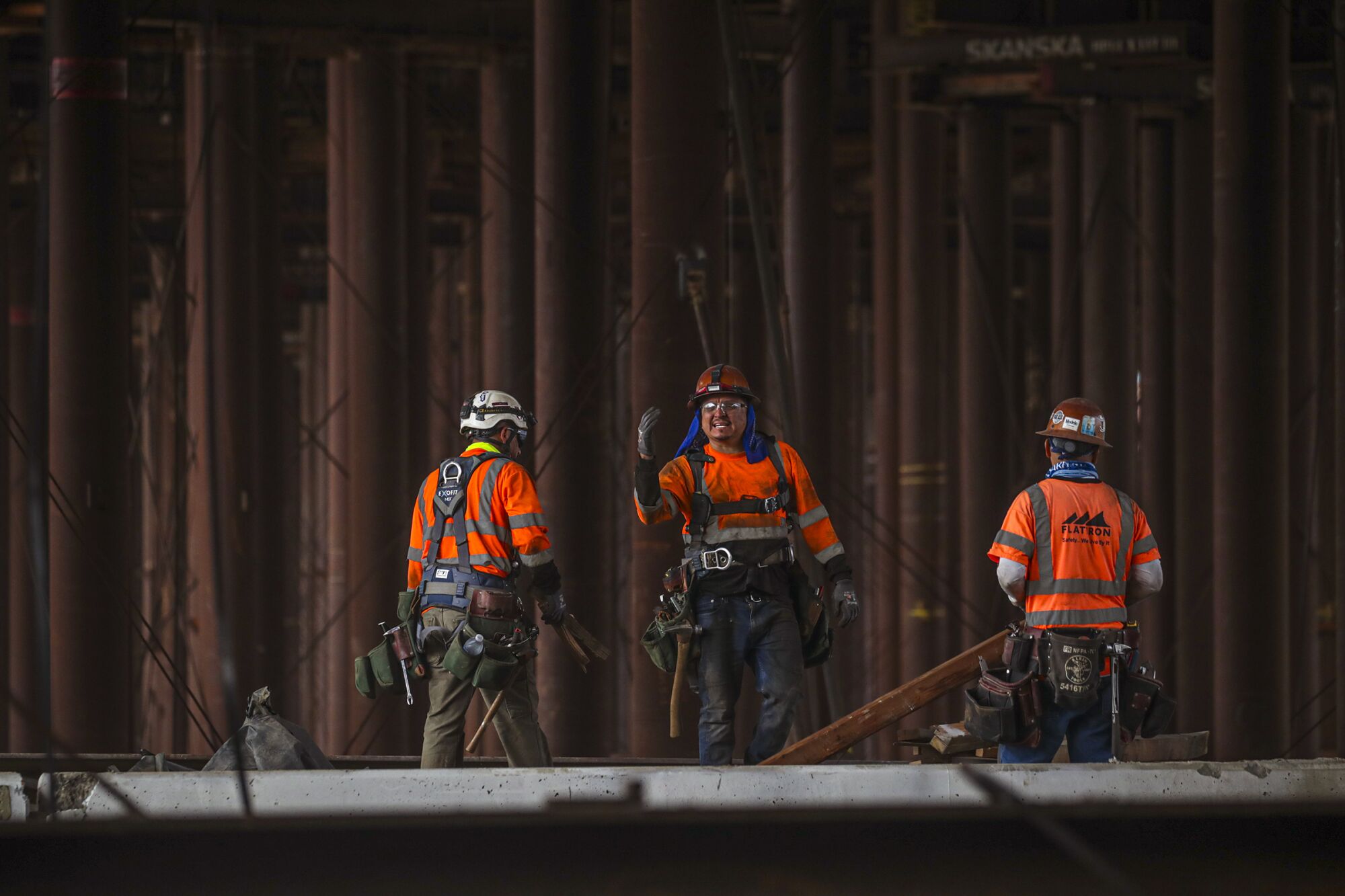 Workers are dwarfed by the massive leg beams under the bridge