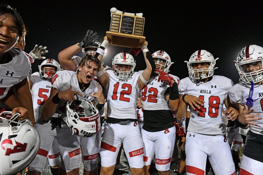 Defensive end Benjamin Medina of Ayala holds up trophy after 20-19 win over Chino Hills.