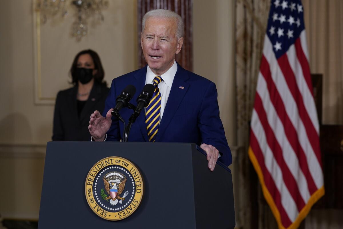 Biden speaks at a podium, with Kamala Harris in the background.