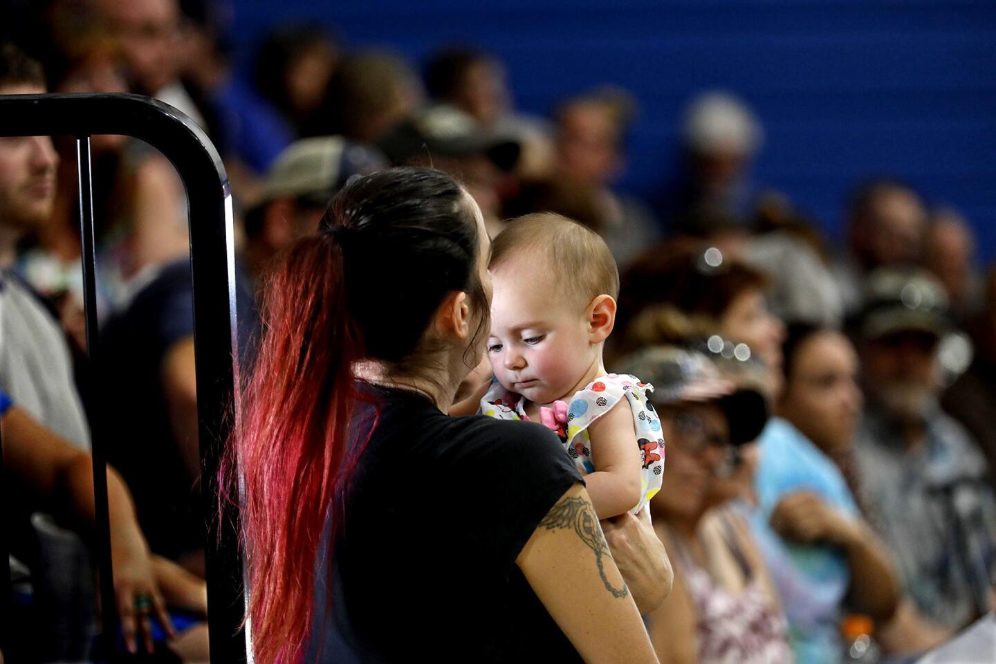 Trona resident Casey Hudgins holds her friend's baby, Allison Jordan, while attending a town hall meeting at Trona High School in Trona, Calif., on Wednesday. Hudgins was forced to leave her home after last week's earthquakes.