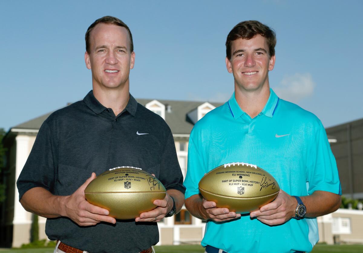 NFL quarterbacks Peyton Manning and Eli Manning pose for a photo during a visit to Isidore Newman School in New Orleans.