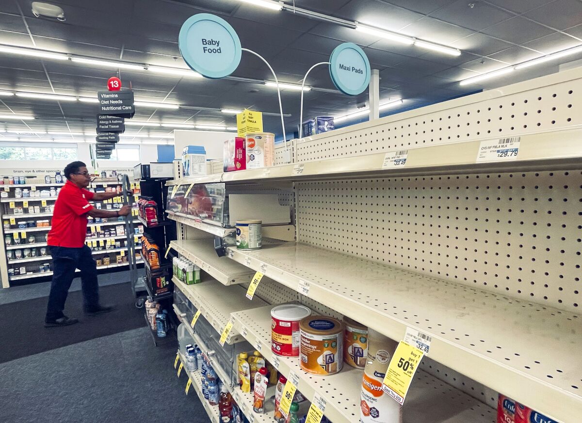 An employee walks near empty shelves where baby formula would normally be located at a CVS in New Orleans on Monday, May 16, 2022. President Joe Biden's administration has announced new steps to ease the national shortage of baby formula, including allowing more imports from overseas. (Chris Granger/The Times-Picayune/The New Orleans Advocate via AP)