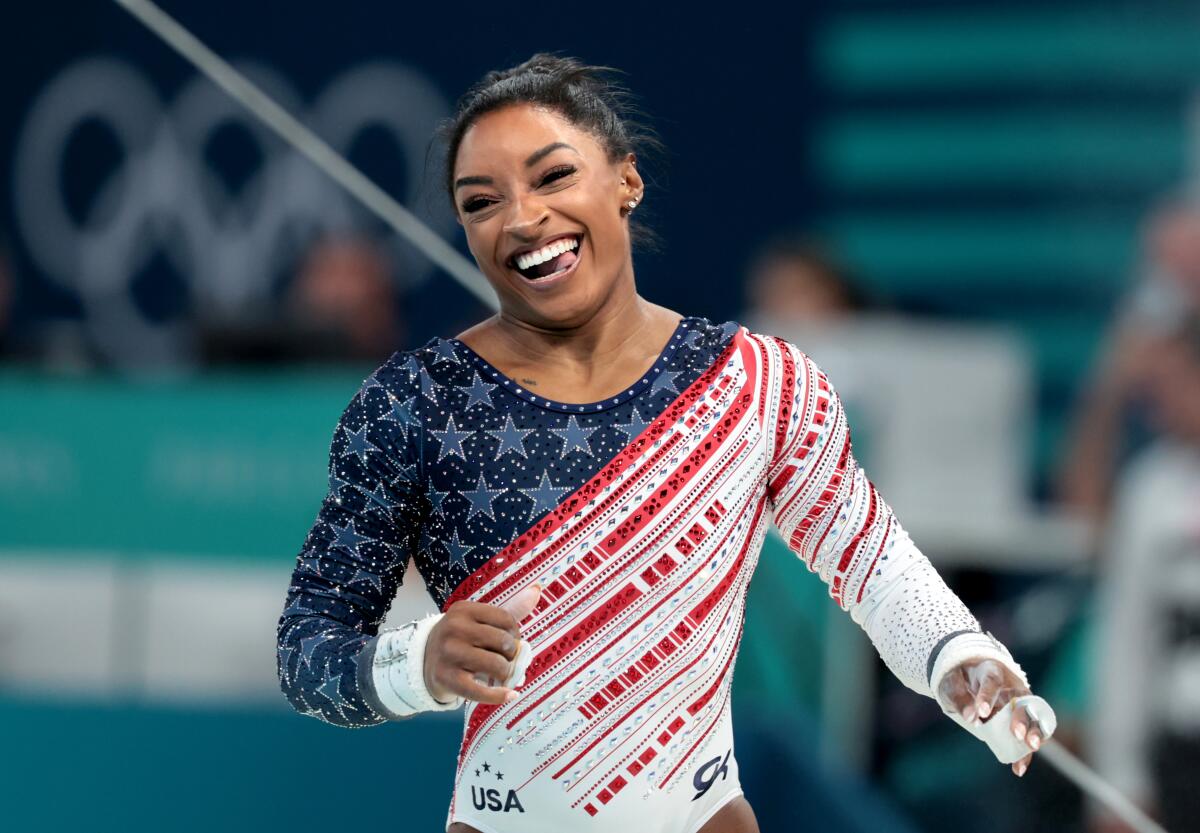 Simone Biles smiles after competing on the uneven bars during the women's gymnastics team final at the 2024 Olympics