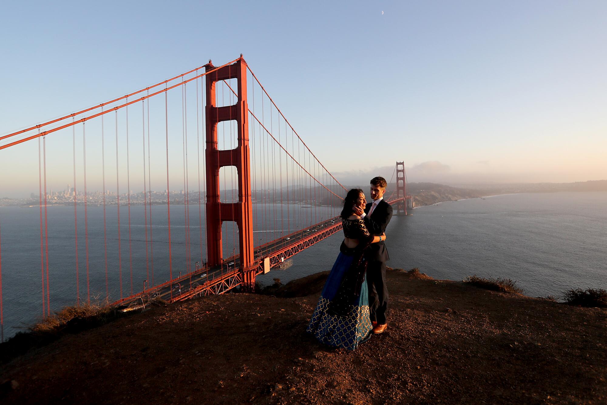 Newlyweds Tulika Jha and Mike Borden take in the sunset at an overlook above the Golden Gate Bridge in San Francisco.