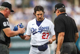 LOS ANGELES, CALIFORNIA - JUNE 28: Umpires check the hat and glove of Trevor Bauer.
