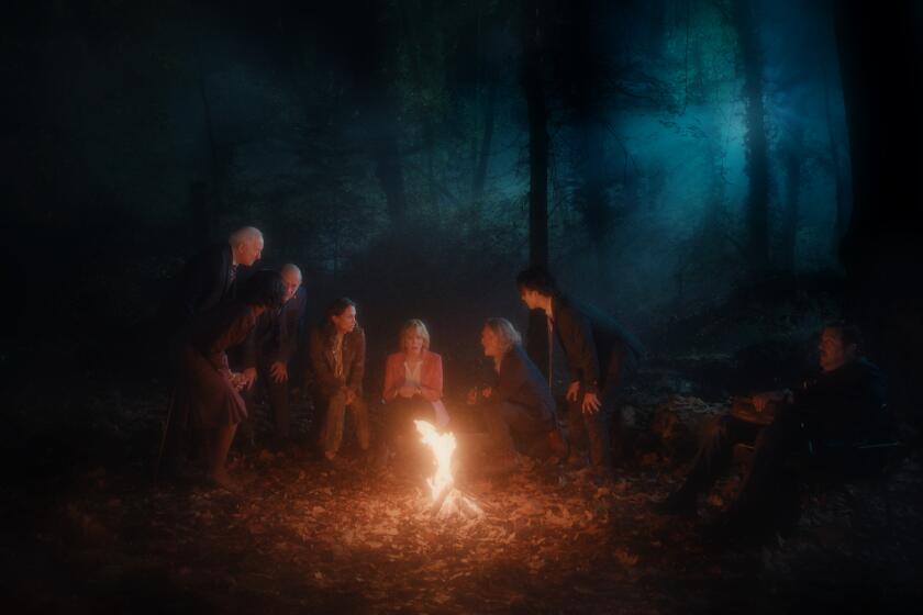 World leaders gather around a fire in the woods.