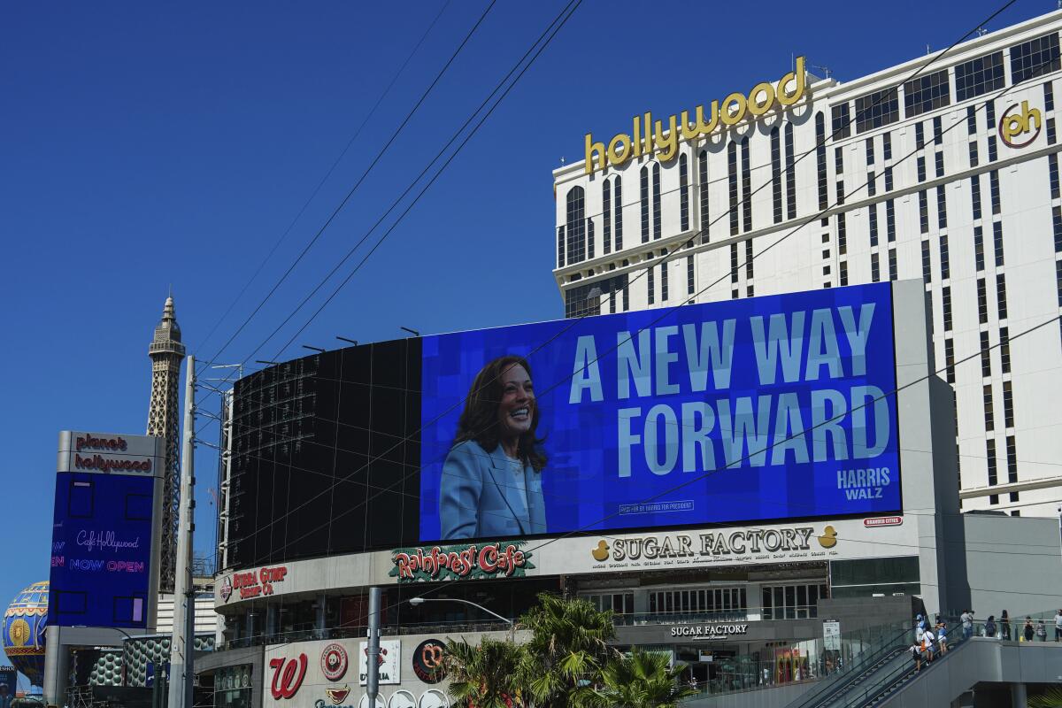 A blue billboard picturing Kamala Harris and reading "A New Way Forward," in front of a Planet Hollywood hotel