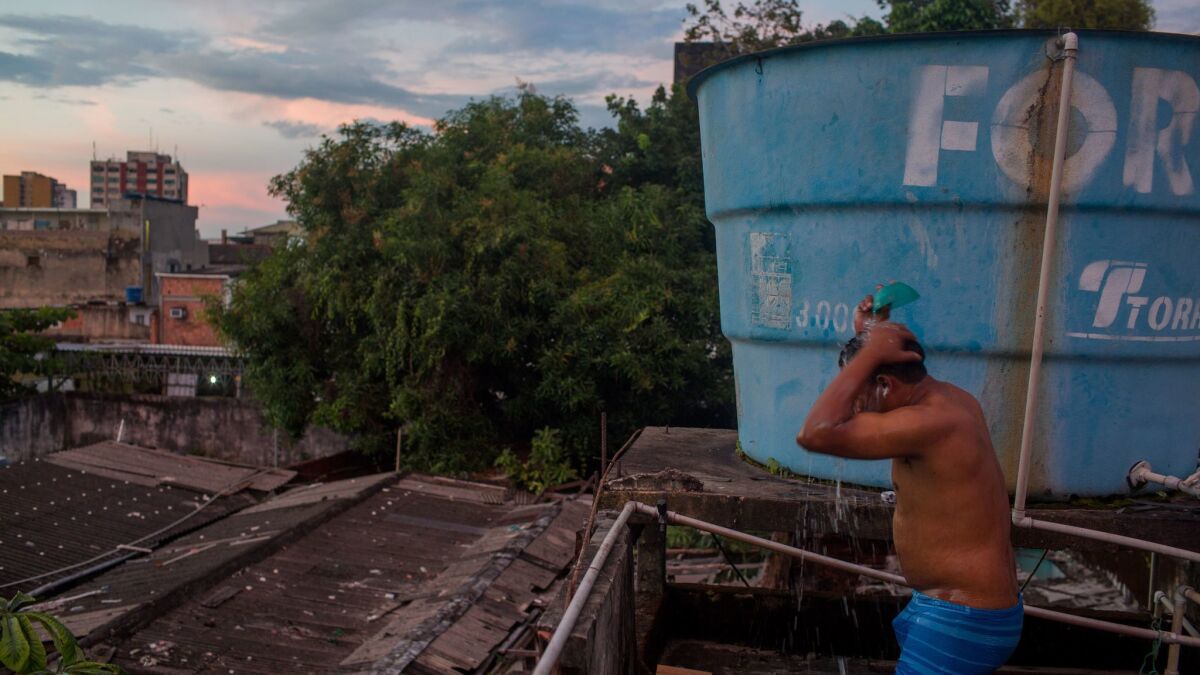A Warao man bathes on a rooftop in Manaus, Brazil. About 350 Warao Indians live in public squares and old mansions in central Manaus. (Victor Moriyama / For The Times)