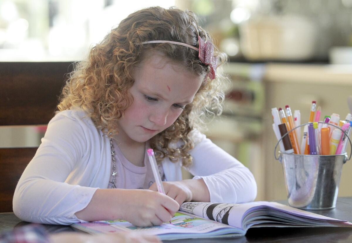 Nina Jensen, 5, works on a pre-kindergarten activity book at home in San Diego on March 19, 2020.