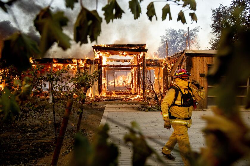Woodbridge Fire Captain Ricardo Ramirez passes a burning home as the Kincade Fire rages in Healdsburg, Calif., on Sunday, Oct 27, 2019. (AP Photo/Noah Berger)