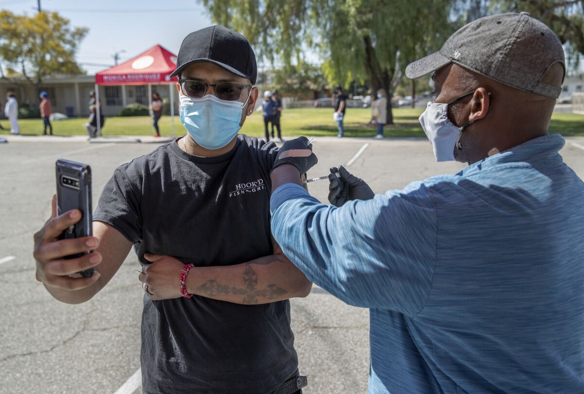 Man takes a video as he receives COVID-19 vaccine in Pacoima