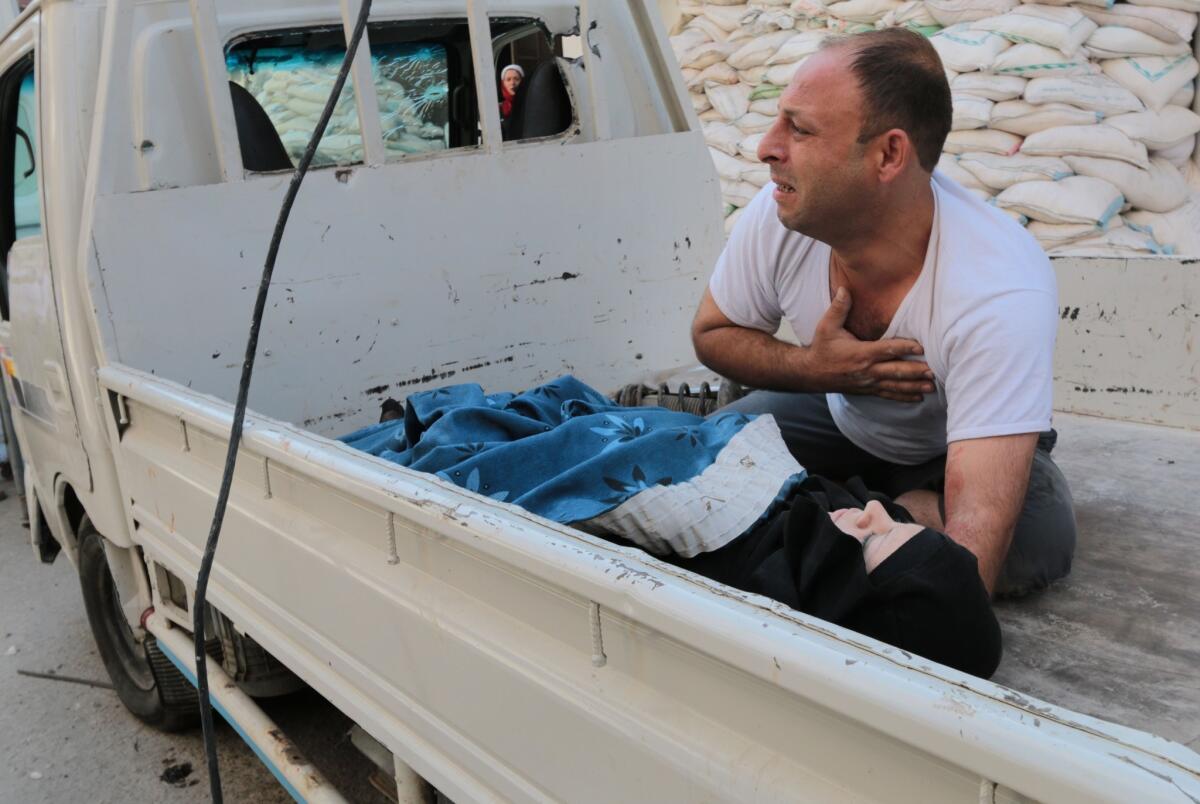 A Syrian man in Aleppo's Shaar neighborhood tends to a victim of a suspected barrel bomb attack on July 9.