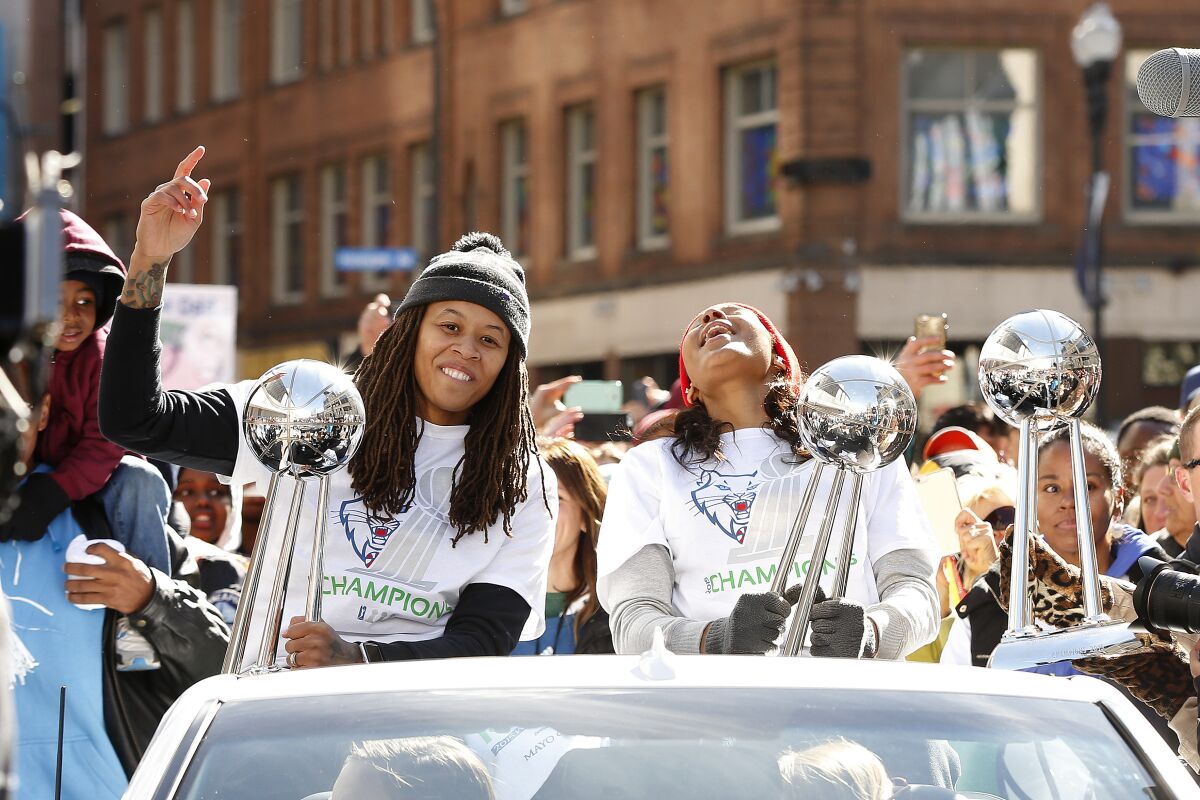 Minnesota Lynx basketball players Seimone Augustus and Maya Moore react to fan cheers during a parade.