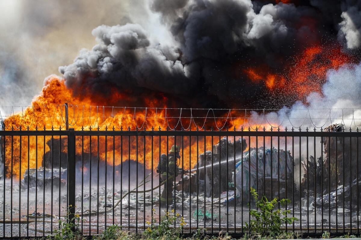 An Ontario firefighter battles huge flames and black smoke while trying to put out a stubborn fire at a recycling plant on East State Street in Ontario.