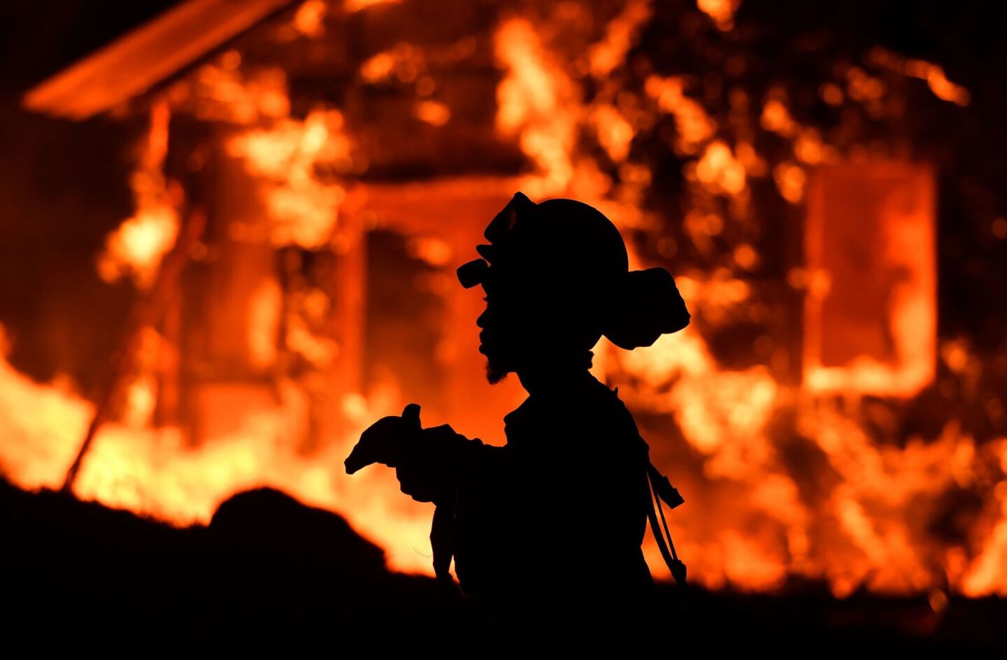 An inmate firefighter monitors flames as a house burns in the Napa wine region.
