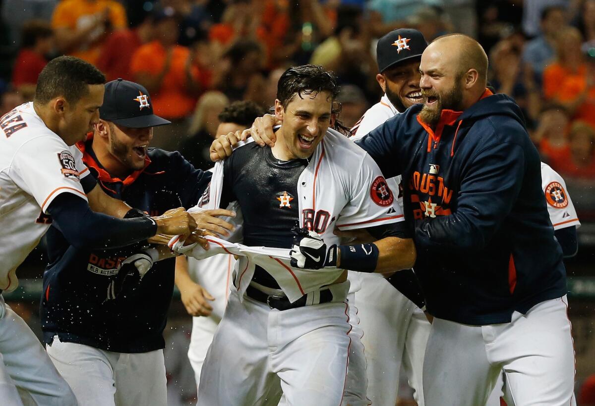 Astros catcher Jason Castro is mobbed and has his jersey ripped off by his teammates after hitting a three-run home run in the ninth inning to win the game against the Angels.