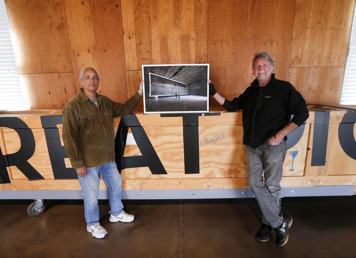 Clayton Spada and Jacques Garnier hold up a print of a photo.