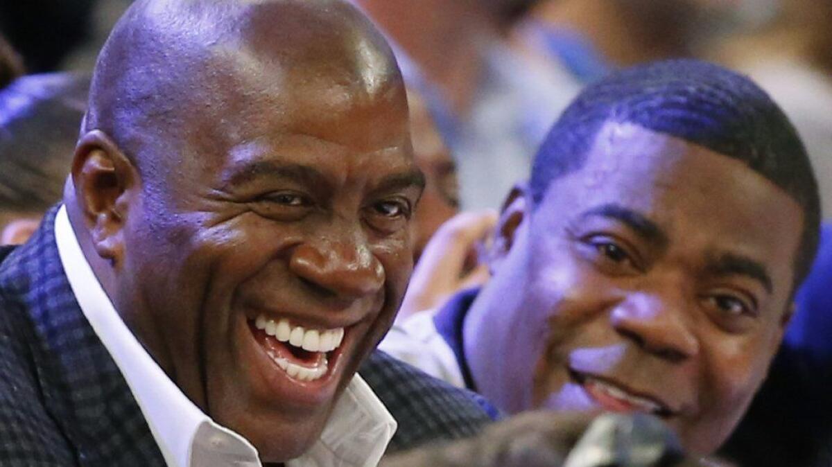 Magic Johnson laughs with comedian Tracy Morgan at a Lakers-Knicks game in 2015. Some fans are not pleased with the prospect of Johnson running the Lakers' front office.