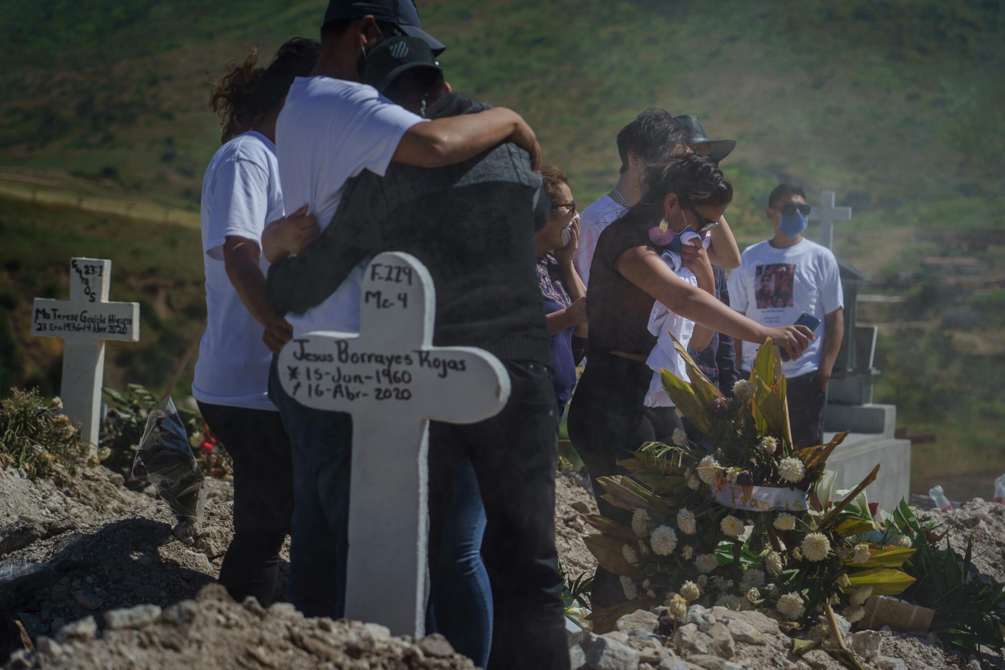  Family members cover their faces as dust kicks up during a funeral.