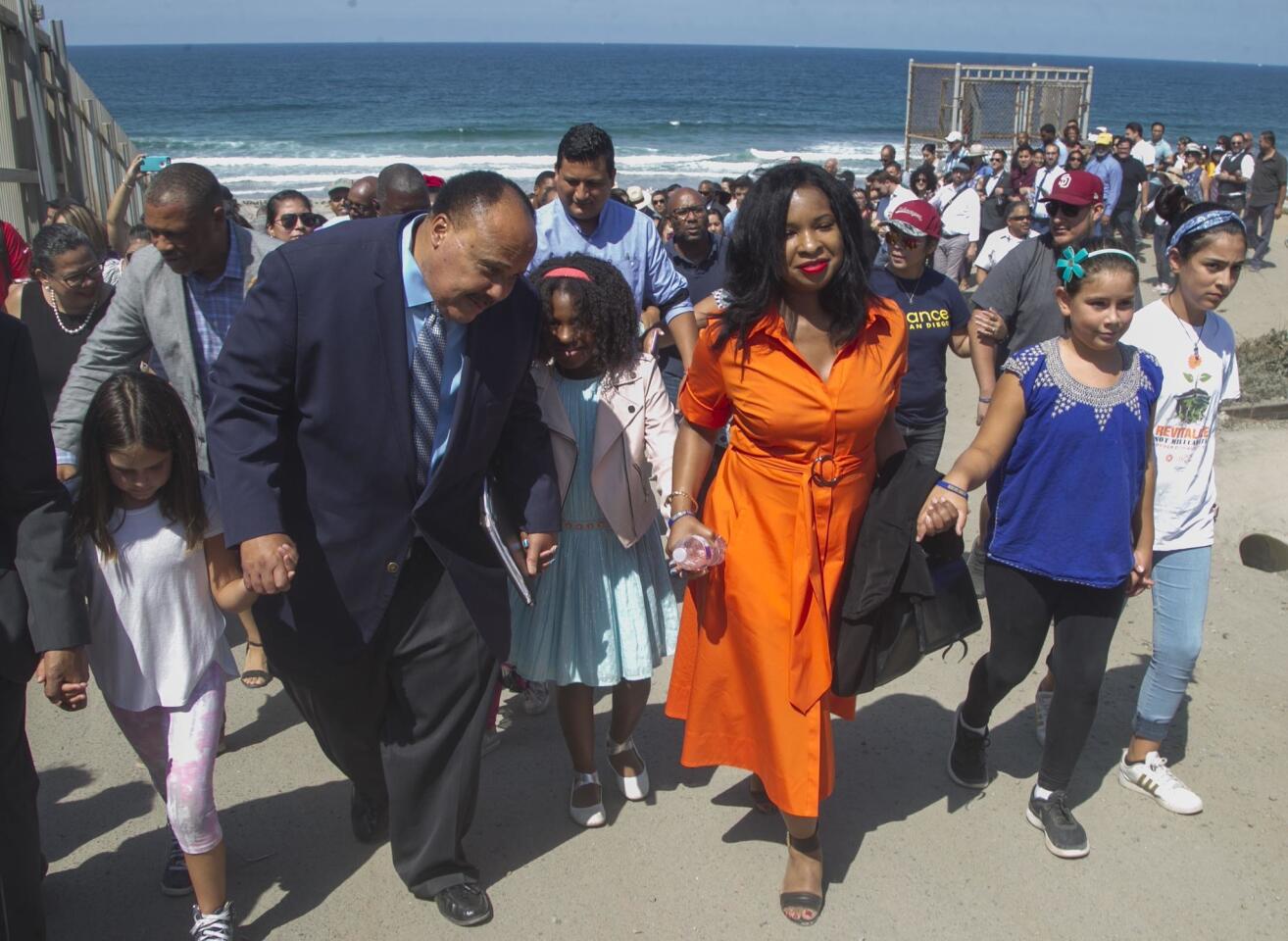 Martin Luther King III, striped tie, his wife Arndrea Waters King, in orange dress, and their daughter Yolanda Renee King, between them, led a group of people from the beach to Border Field State Park where King gave a speech, to commemorate the 55th anniversary of his father's "I Have a Dream" speech 55 years ago. He spoke out strongly denounced the dehumanizing treatment of immigrants and their families along the border region. PHOTO/JOHN GIBBINS Staff photographer, San Diego Union-Tribune. ©2018
