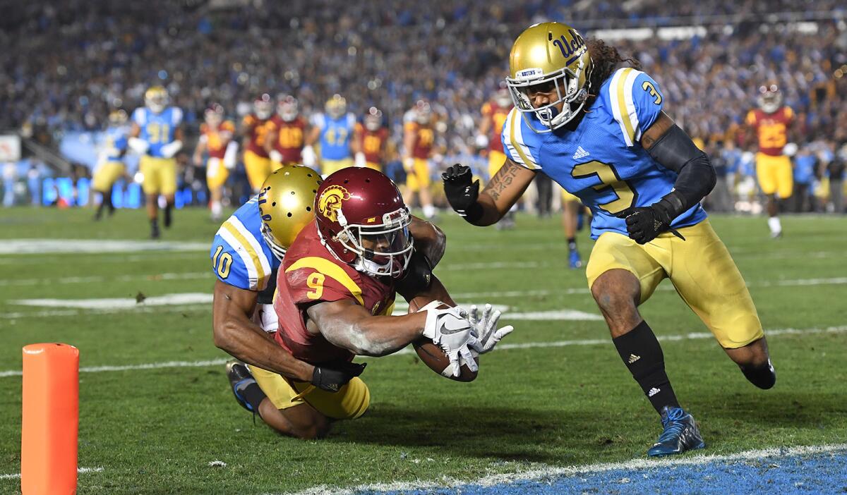 USC receiver Juju Smith-Schuster is tackled at the one-yard line by UCLA's Fabian Moreau as Randall Goforth closes in during the first quarter on Saturday.