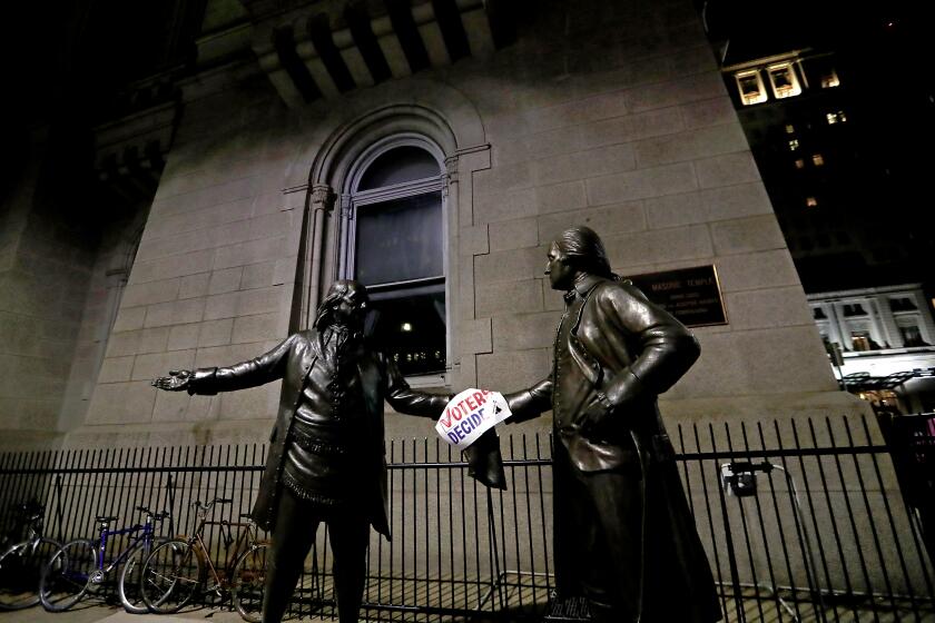 Statues of national heroes Benjamin Franklin, left, and George Washington hold a sign that says "Voters Decide"