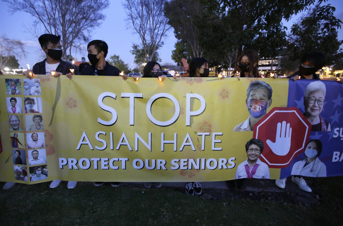 Demonstrators at a vigil hold a sign that says Stop Asian Hate Protect Our Seniors