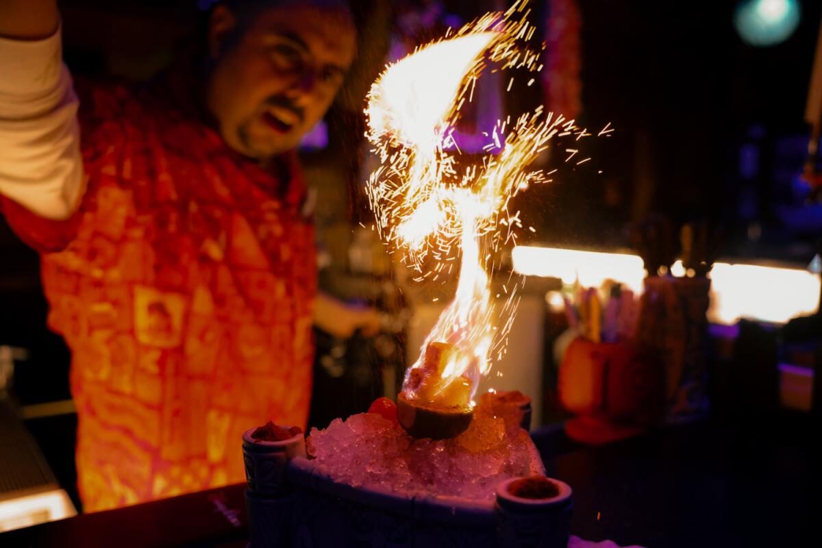 A bartender lights a tropical cocktail on fire