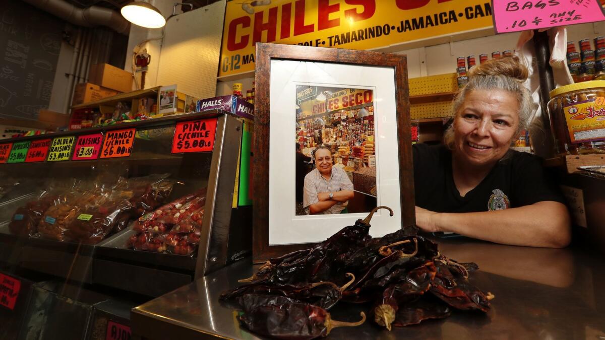 Rocio Lopez next to a photograph of her father, Celestino Lopez, at the Chiles Secos stand inside Grand Central Market. Celestino started working at the market in 1970 and eventually bought the stand, which he later passed on to his family.