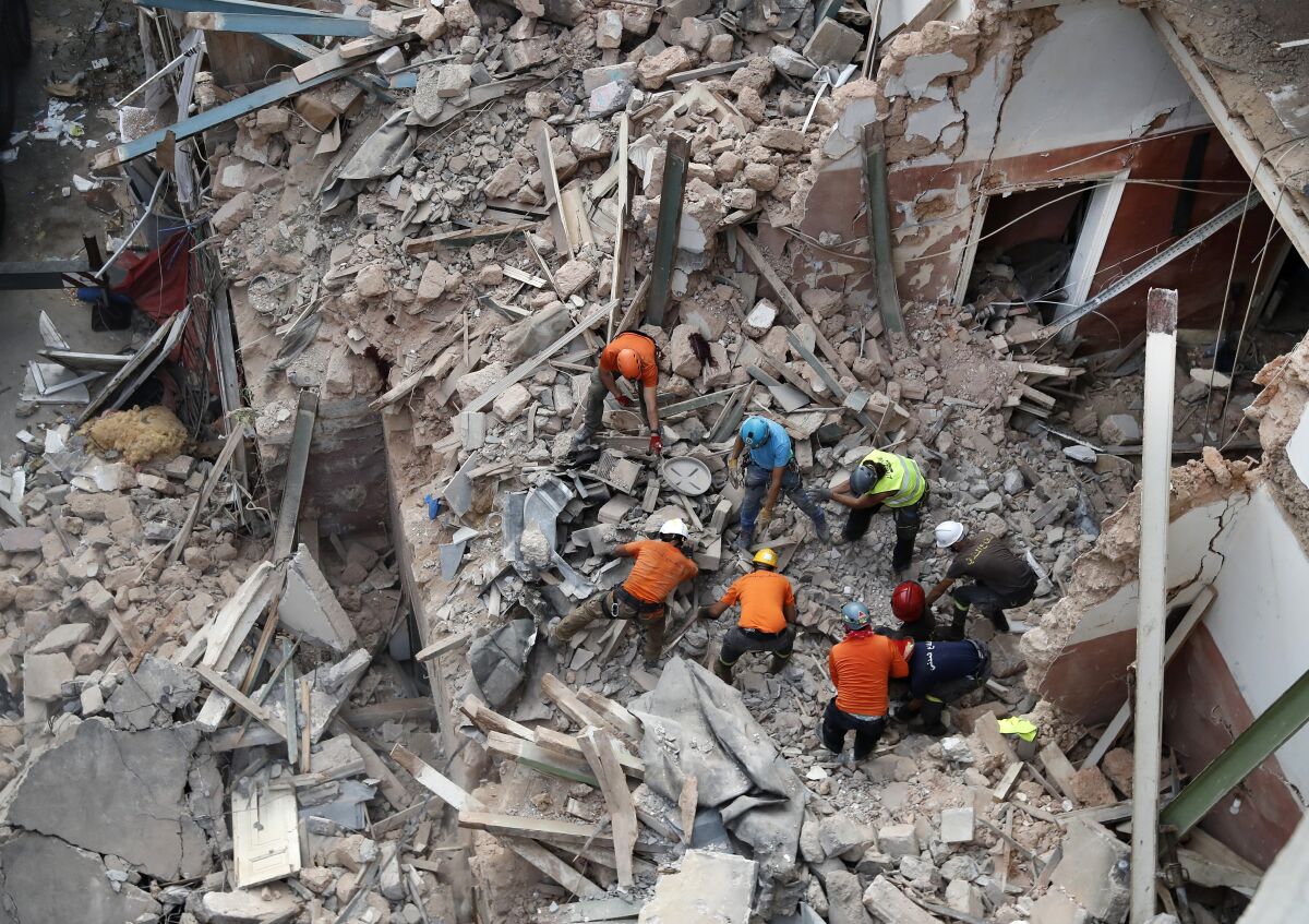 Lebanese and Chilean rescuers search in the rubble of a collapsed building after getting signals there may be a survivor, early Friday, Sept. 4, 2020, in Beirut, Lebanon. A pulsing signal was detected Thursday from under the rubble of a Beirut building that collapsed during the horrific port explosion in the Lebanese capital last month, raising hopes there may be a survivor still buried there. (AP Photo/Hussein Malla)