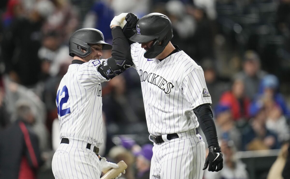 Colorado Rockies' Ryan McMahon, left, congratulates C.J. Cron on a solo home run off Chicago Cubs relief pitcher Chris Martin during the fifth inning of a baseball game Friday, April 15, 2022, in Denver. (AP Photo/David Zalubowski)