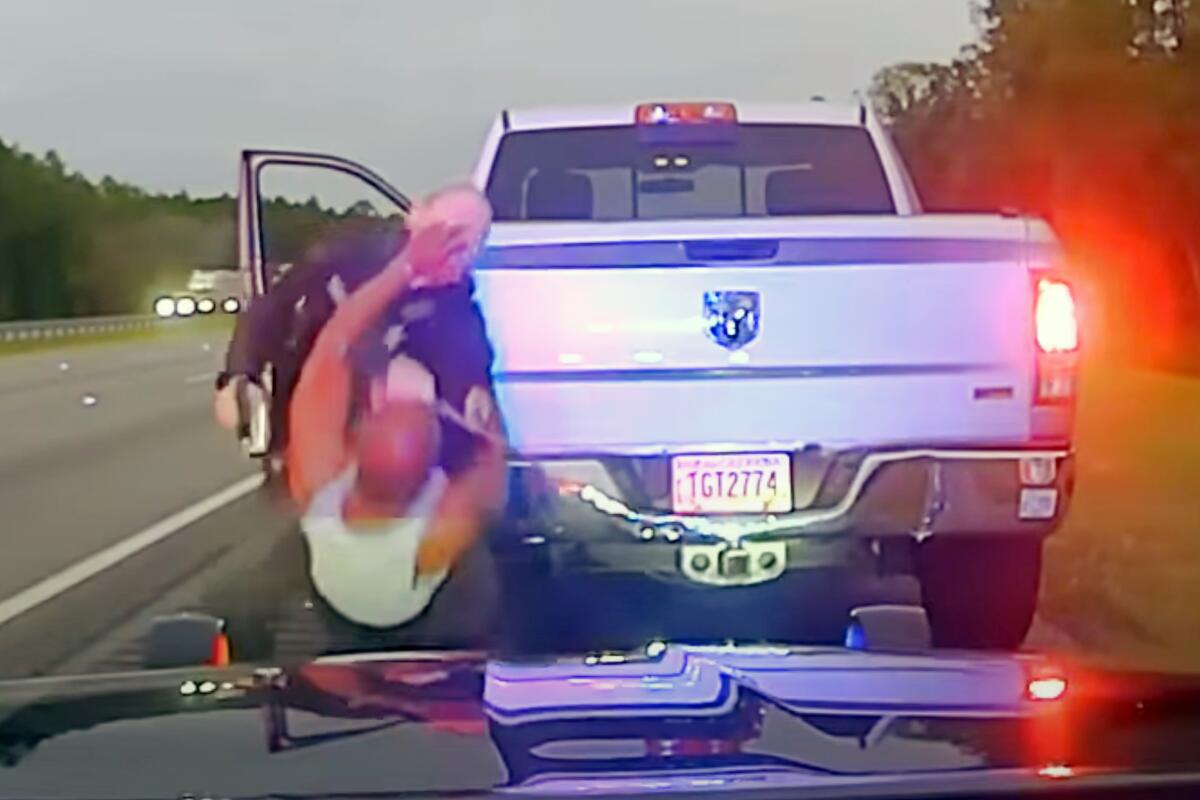 A scene from dash-cam video shows man falling backward in front of sheriff’s official on a roadside near a truck