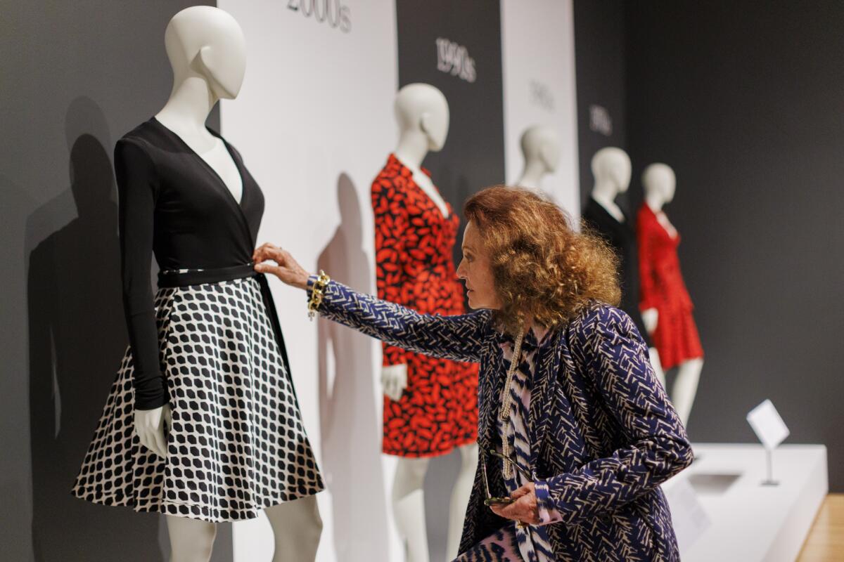 Diane von Furstenberg examines a line of mannequins in her wrap dresses