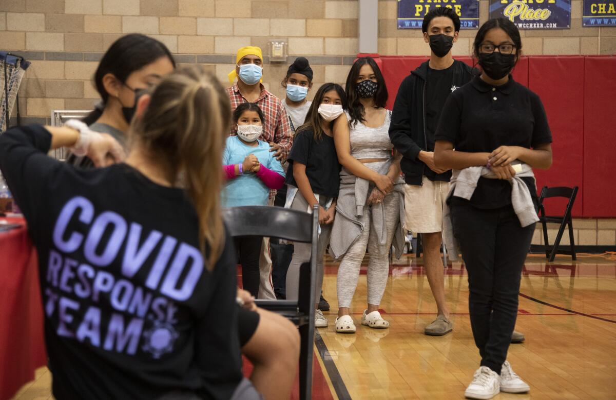 Children wait with their parents for the COVID-19 vaccine at Arleta High School