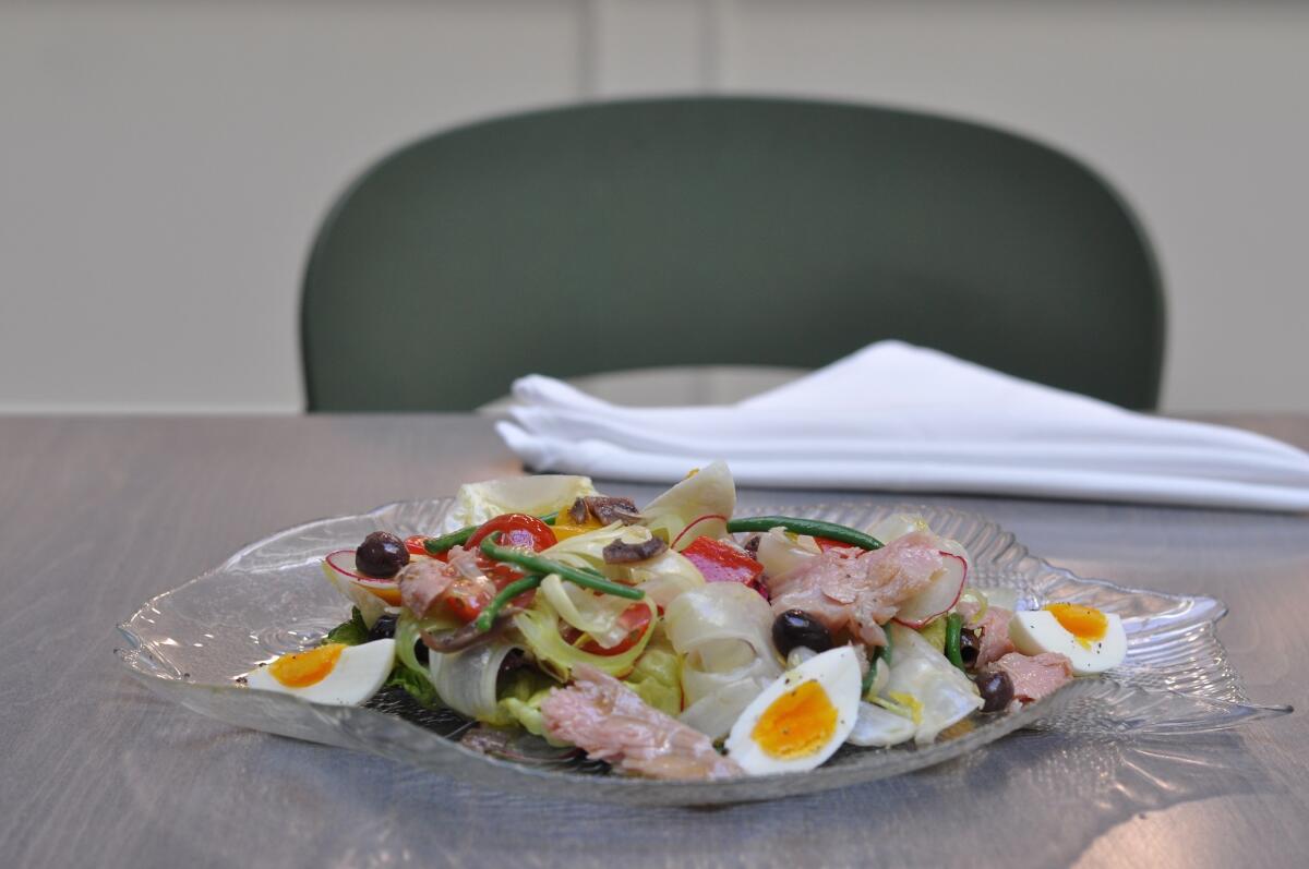 Salade Riviera, with tuna confit fennel, tomatoes, anchovies, olives, egg and lettuces, is served on a glass fish plate at Spring.