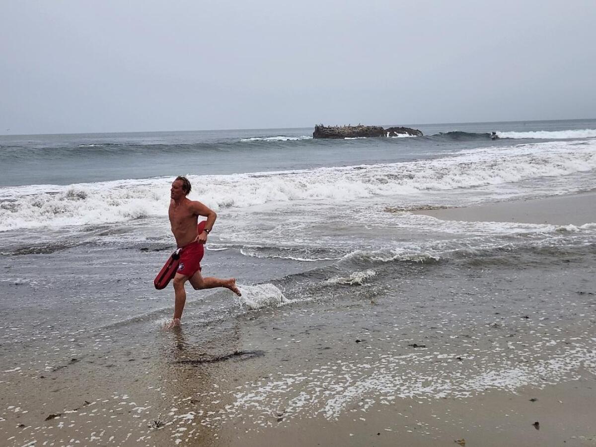 A lifeguard runs back to Main Beach after advising surfers in Laguna Beach on Sunday.