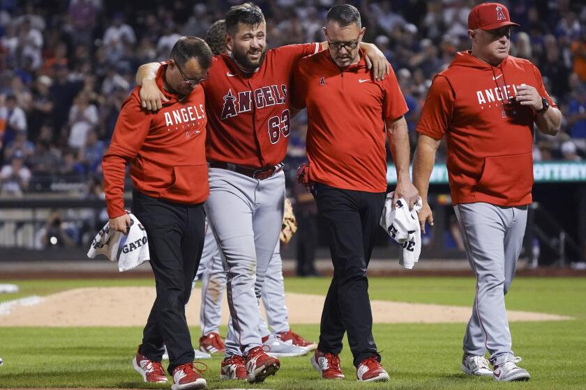Los Angeles Angels starting pitcher Chase Silset, second from left, is assisted off the field.