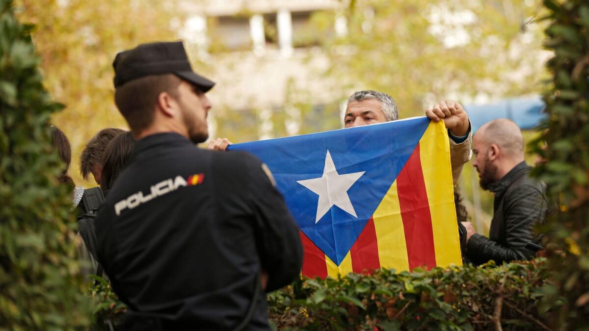 A man holds a Catalonia independence flag in front of a national police officer outside the National Court in Madrid on Nov. 2, 2017.