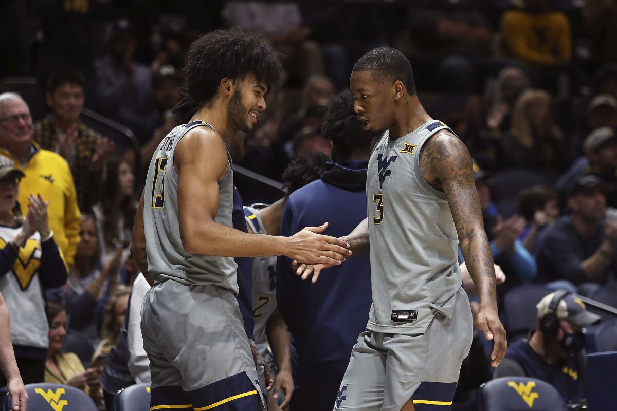 West Virginia forwards Isaiah Cottrell (13) and Gabe Osabuohien (3) celebrate after a score against Oklahoma State during the first half of an NCAA college basketball game in Morgantown, W.Va., Tuesday, Jan. 11, 2022. (AP Photo/Kathleen Batten)